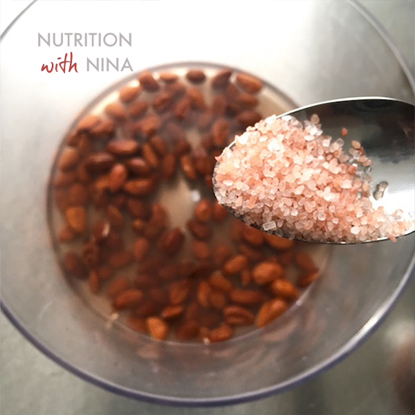 SPOON OF PINK HIMALAYAN SALT AND BOWL OF SOAKED ALMONDS