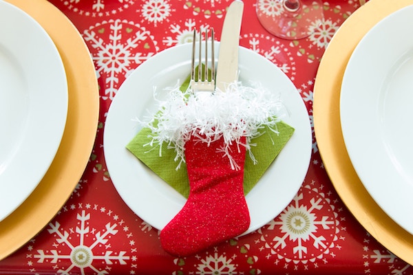 white plate and red christmas stocking on a red snowflake tablecloth