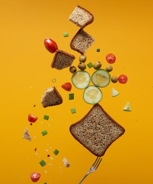 Nutrition-with-Nina-Digestive-MOT-Test-tangerine-newt Bread, cucumber, berries balanced on a silver fork on a vibrant orange background-Nutrition with Nina DigestiveMOT is a testing service to uncover factors that upset your digestive balance