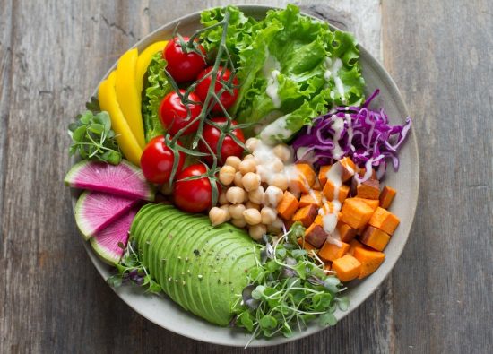 Bowl of delicious mix of of foods including avocado, cherry tomatoes, chickpeas, sweet potato and cabbage to break out of a food routine.