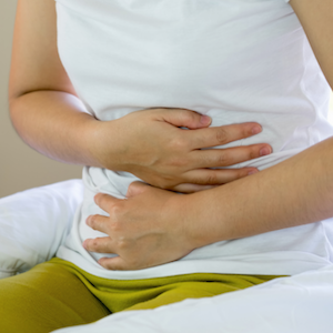 Woman, sitting holding her stomach in pain - Nutrition with Nina Digestive MOT